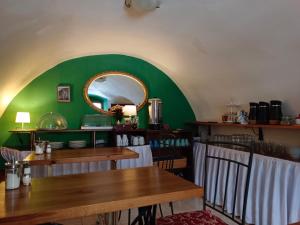 a dining room with green walls and wooden tables at Guest House Olšakovský in Český Krumlov