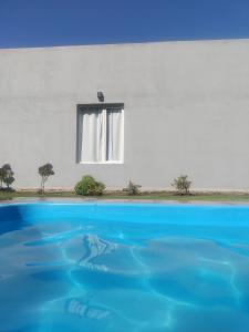 een wit huis met een raam en blauw water bij Los nogales in Tandil