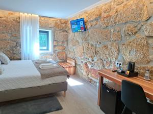 a bedroom with a stone wall with a bed and a desk at Agrafonte in Paços de Ferreira