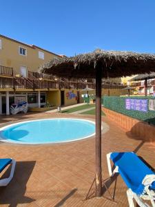 a swimming pool with a straw umbrella and chairs at Casa Greta in Costa de Antigua