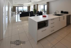 a kitchen with a white island with a microwave at “CALLINGTON” Darwin City @PenthousePads in Darwin