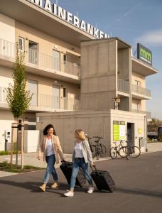 dos mujeres caminando por la calle con su equipaje en Mainfranken Motel - Anreise rund um die Uhr - Neueröffnung 2023, 