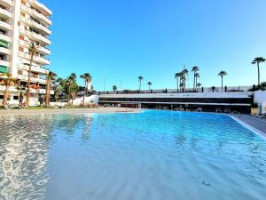 a large swimming pool next to a building with palm trees at Un pisito en Maspalomas in Maspalomas
