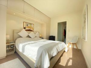 een slaapkamer met een groot wit bed en een stoel bij Zeedijk Koksijde in Koksijde