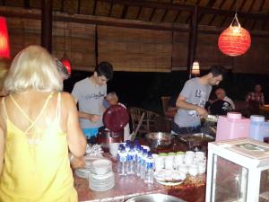 a group of people standing around a table with food at Beten Waru Bungalow and Restaurant in Amed