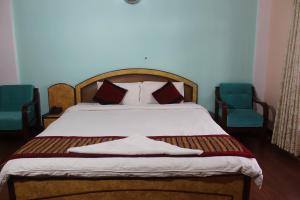 a bedroom with a bed with two blue chairs at Hotel Happy Home or Mudkhu Durbar in Kathmandu