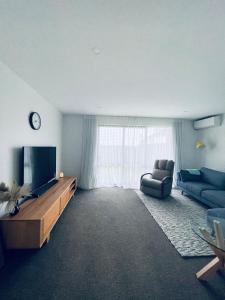 a living room with a television and a couch at Stylish Industrial Holiday House in Pakuranga Free Wifi Netflix in Auckland