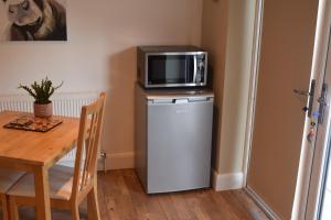 a microwave sitting on top of a refrigerator next to a table at Cherry Farmhouse in York