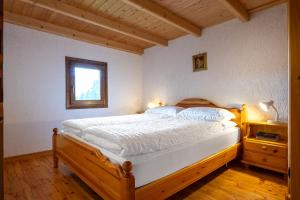 a bedroom with a bed with a wooden frame and a window at Baita Vioz in Peio