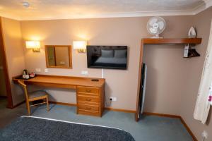 een kamer met een bureau en een tv aan de muur bij Bridge Inn in Clevedon