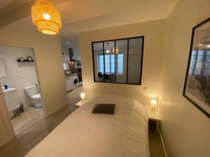 1 Schlafzimmer mit einem weißen Bett und einem Badezimmer in der Unterkunft Grand studio entrée SPA incluse in Bourbon-Lancy
