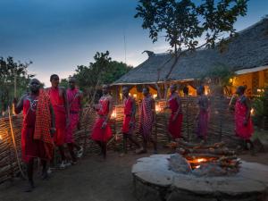 a group of people standing around a fire pit at Kilima Camp - Safari in Masai Mara in Lolgorien