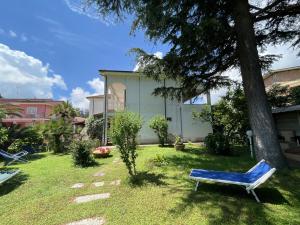 a blue bench sitting in the grass next to a tree at Appartamenti Adriana di ArgonautiVacanze in Porto Azzurro