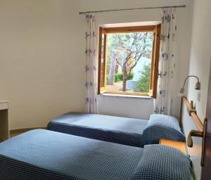 two beds in a room with a window at Villaggio Turistico La Mantinera - Residence in Praia a Mare +58 photos