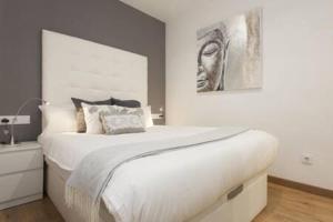 Un dormitorio con una gran cama blanca y una pintura en Designer Apt near FIRA Balcony 5PPWIFISMART TV by MyRentalHost, en Hospitalet de Llobregat