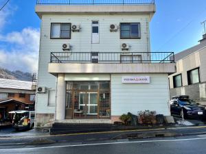 a white building with a balcony on top of it at Yuzawa house in Yuzawa