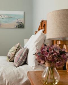 a bed with pillows and a table with a lamp at Sea Sound in Cellardyke