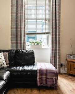 um sofá de couro preto numa sala de estar com uma janela em Sea Sound em Cellardyke