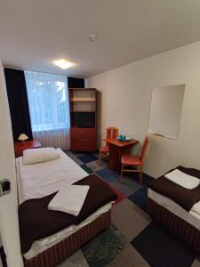 a hotel room with two beds and a desk at Płonia Economy in Szczecin