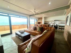 a living room with leather couches and a view of the ocean at Mitford The N I C E Condo in Morganʼs Bay