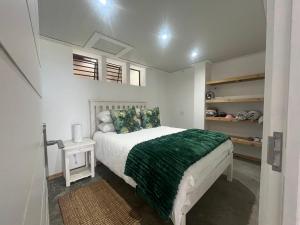 a bedroom with a bed with a green blanket at Mitford The N I C E Condo in Morganʼs Bay