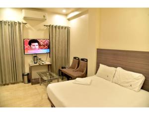um quarto de hotel com uma cama e uma televisão de ecrã plano em Hotel Dwarka, Nagpur em Nagpur
