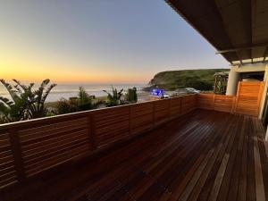 a deck with a view of the beach at sunset at Mitford The N I C E Condo in Morganʼs Bay