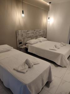 two beds in a hotel room with towels on them at Evita Blue in Xylokastro +16 photos