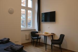 a room with a table and chairs and a tv on the wall at Riverside Apartments in Linz
