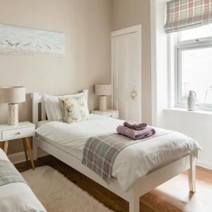 a bedroom with a white bed with two lamps and a window at Sea Sound in Cellardyke