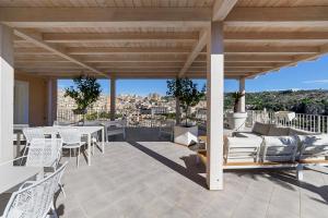 a patio with white chairs and tables on a roof at Itria Modica in Modica