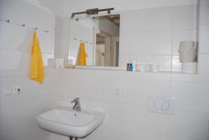 a white bathroom with a sink and a mirror at Ferienhaus Meerblick in Sierksdorf