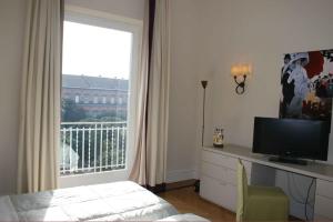 a bedroom with a television and a window with a balcony at Residence gli Angioini srl in Naples