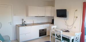 a kitchen with white cabinets and a table and a tv at Pension Zandvoort aan Zee in Zandvoort +22 photos