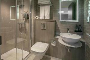 a bathroom with a shower and a toilet and a sink at Best Western Plus Vauxhall Hotel in London