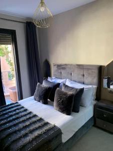 um quarto com uma cama grande e almofadas pretas e brancas em Appartement neuf climatisé, centre Marrakech. em Marrakech