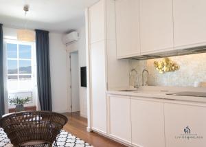 a kitchen with white cabinets and a chair at Living4malaga Atico Marina in Málaga
