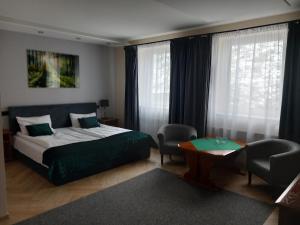 1 dormitorio con cama, mesa y ventanas en Hotel Baltazar, en Pułtusk