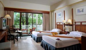 a hotel room with three beds and a balcony at Karon Princess Hotel SHA EXTRA Plus in Karon Beach