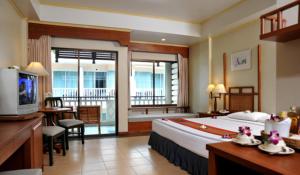 ein Hotelzimmer mit einem großen Bett und einem Balkon in der Unterkunft Karon Princess Hotel SHA EXTRA Plus in Karon Beach