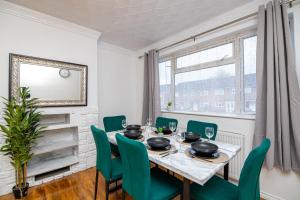 ein Esszimmer mit einem Tisch und grünen Stühlen in der Unterkunft Impeccable 3-Bed House in Abbeywood in London