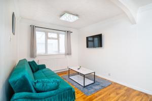 Impeccable 3-Bed House in Abbeywood في لندن: غرفة معيشة مع أريكة خضراء وطاولة