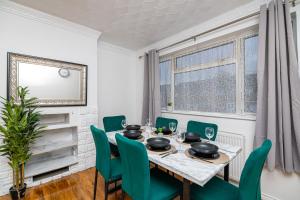 ein Esszimmer mit einem Tisch und grünen Stühlen in der Unterkunft Impeccable 3-Bed House in Abbeywood in London