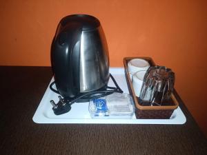 a black appliance sitting on a white plate with a tray of items at Hotel Sayee luxury Inn in Pune