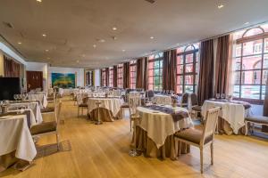 Un salón de banquetes con mesas, sillas y ventanas. en Hotel Blancafort Spa Termal, en La Garriga