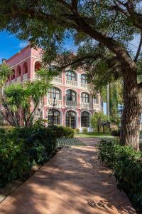 a pink building with trees in front of it at Hotel Blancafort Spa Termal in La Garriga