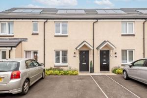 two cars parked in a parking lot in front of a house at Fort Avenue - No 31 Guardbridge in Guardbridge