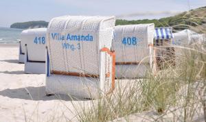 a row of white chairs sitting on the beach at Villa Amanda by Rujana in Binz