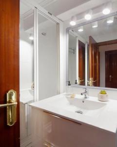 bagno con lavandino bianco e specchio di Apartamento Maura 2 dormitorios a Oviedo