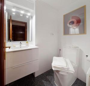 y baño con lavabo, aseo y espejo. en Apartamento Maura 2 dormitorios, en Oviedo